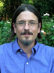 Photo of poet, Adam Houle with landscape behind him