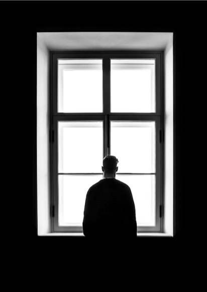 black and white image of man looking out a window