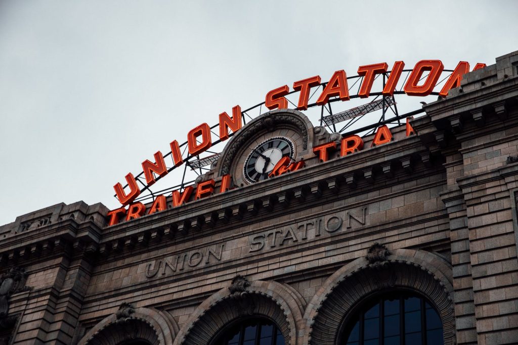 Illuminated sign of Union Station against the architectural detail of the historical building's facade in Denver