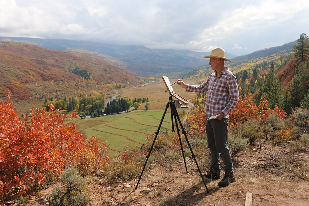 Artist Jay Moore painting with a serene Colorado view