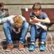 two young boys playing on their phones on a curbside.